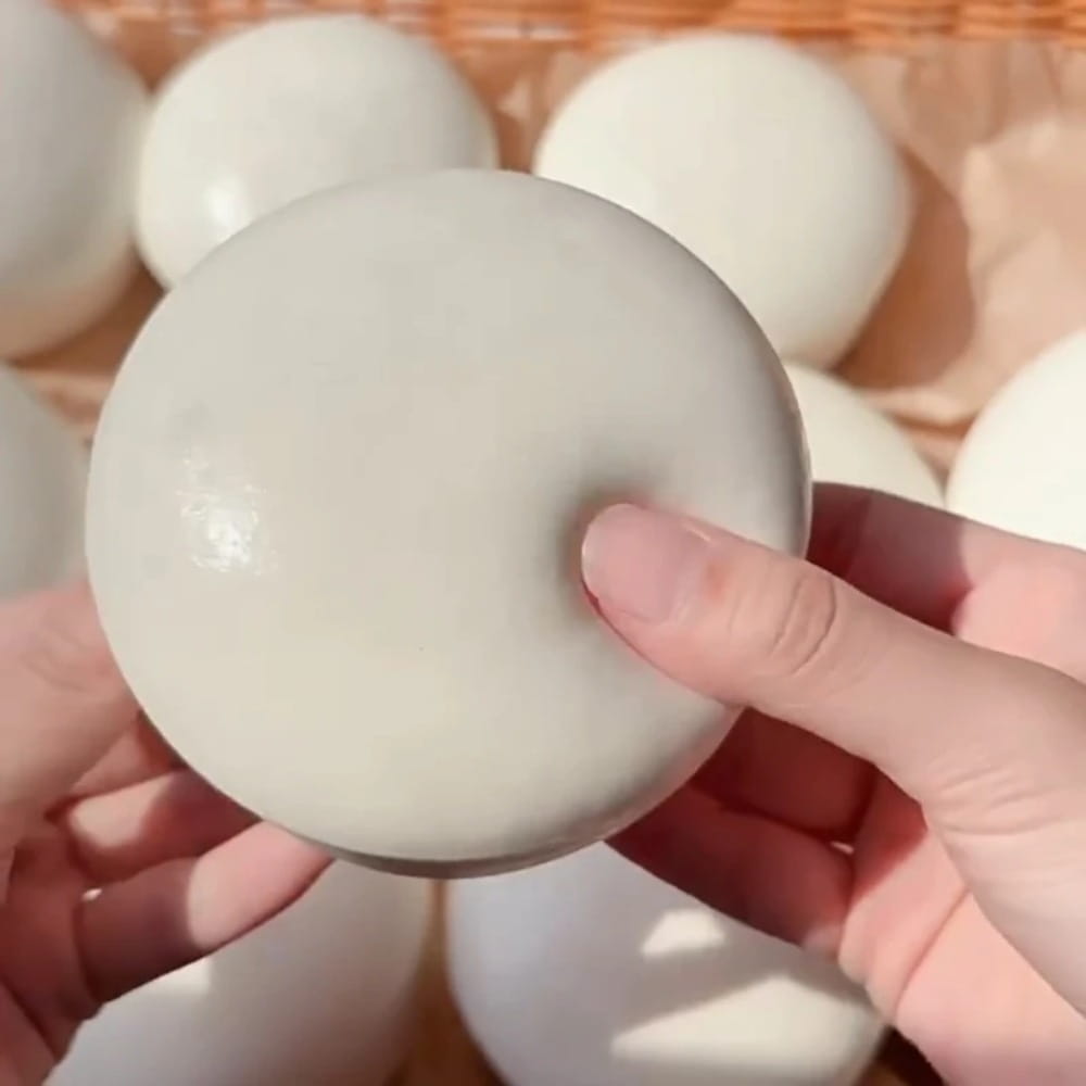 Jouet antistress souple en forme de gâteau au yaourt rond blanc cassé, à surface légèrement brillante et texture lisse.