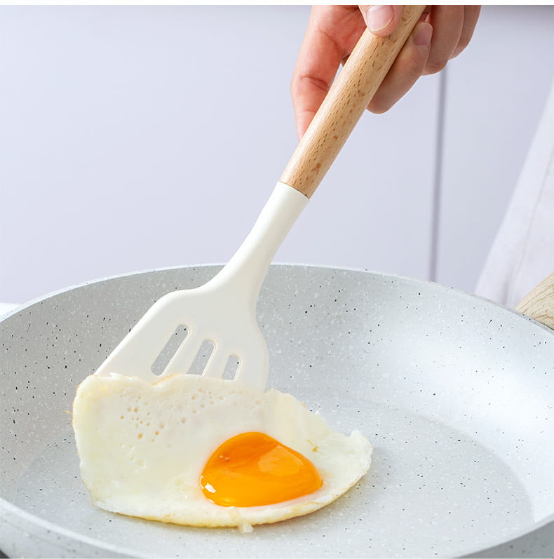 White silicone kitchen spatula with wooden handle and three slots designed for cooking and baking tasks.
