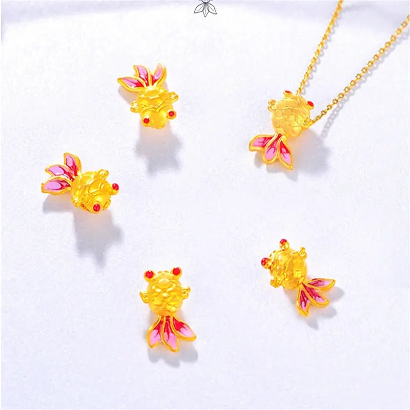 Collier pendentif poisson en or 24 carats, doté de breloques en forme de poisson avec des nageoires émaillées roses et des yeux sertis de pierres rouges, conçu pour être porté en collier.
