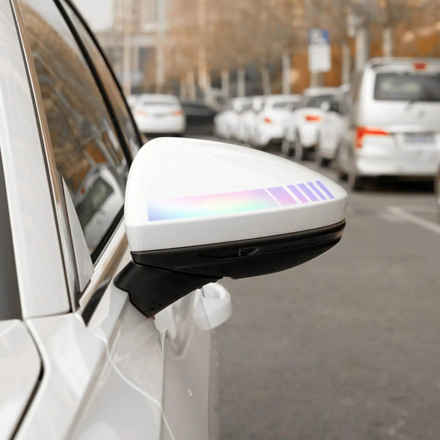 Miroir latéral de voiture blanc comportant une bande lumineuse LED de couleur arc-en-ciel le long de son bord supérieur, dans un lot d’autocollants vinyle rayés pour rétroviseurs.