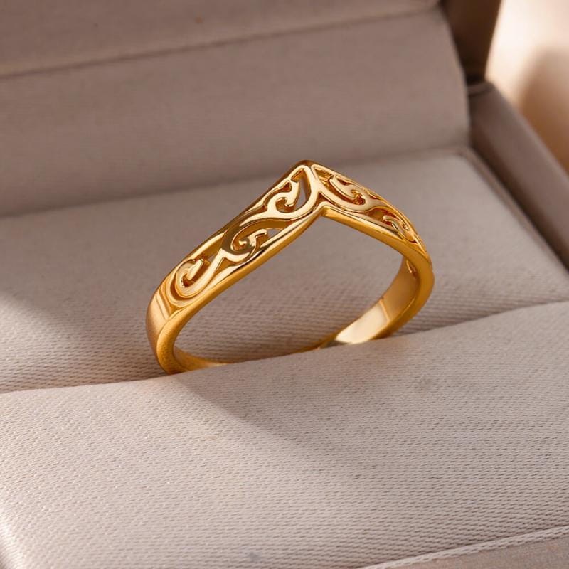 A gold color stainless steel ring for women with intricate swirling filigree patterns displayed in a soft-textured presentation box.