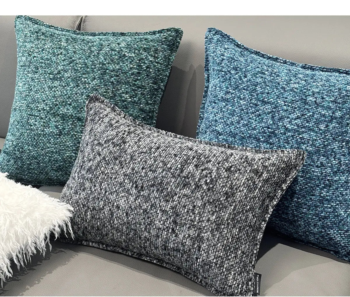 Trois housses de coussin d’appoint en chenille texturées dans des tons bleu canard et gris, avec une finition de tissu tissé pour un usage décoratif