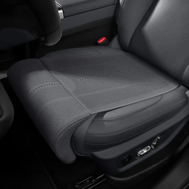 Schwarzer, perforierter Sitzbezug aus Mesh mit vernähten Kanten und konturiertem Design zur Unterstützung der Beinkissenpartie auf einem braun perforierten Fahrzeugsitzkissen.