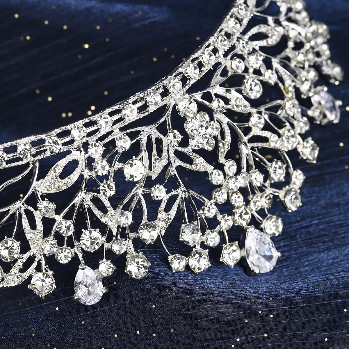 Une tiare de mariage en cristal d'argent étincelant, ornée de motifs complexes de feuilles et de branches, ainsi que de cristaux transparents en forme de goutte, en cascade, pour un usage lors du mariage.