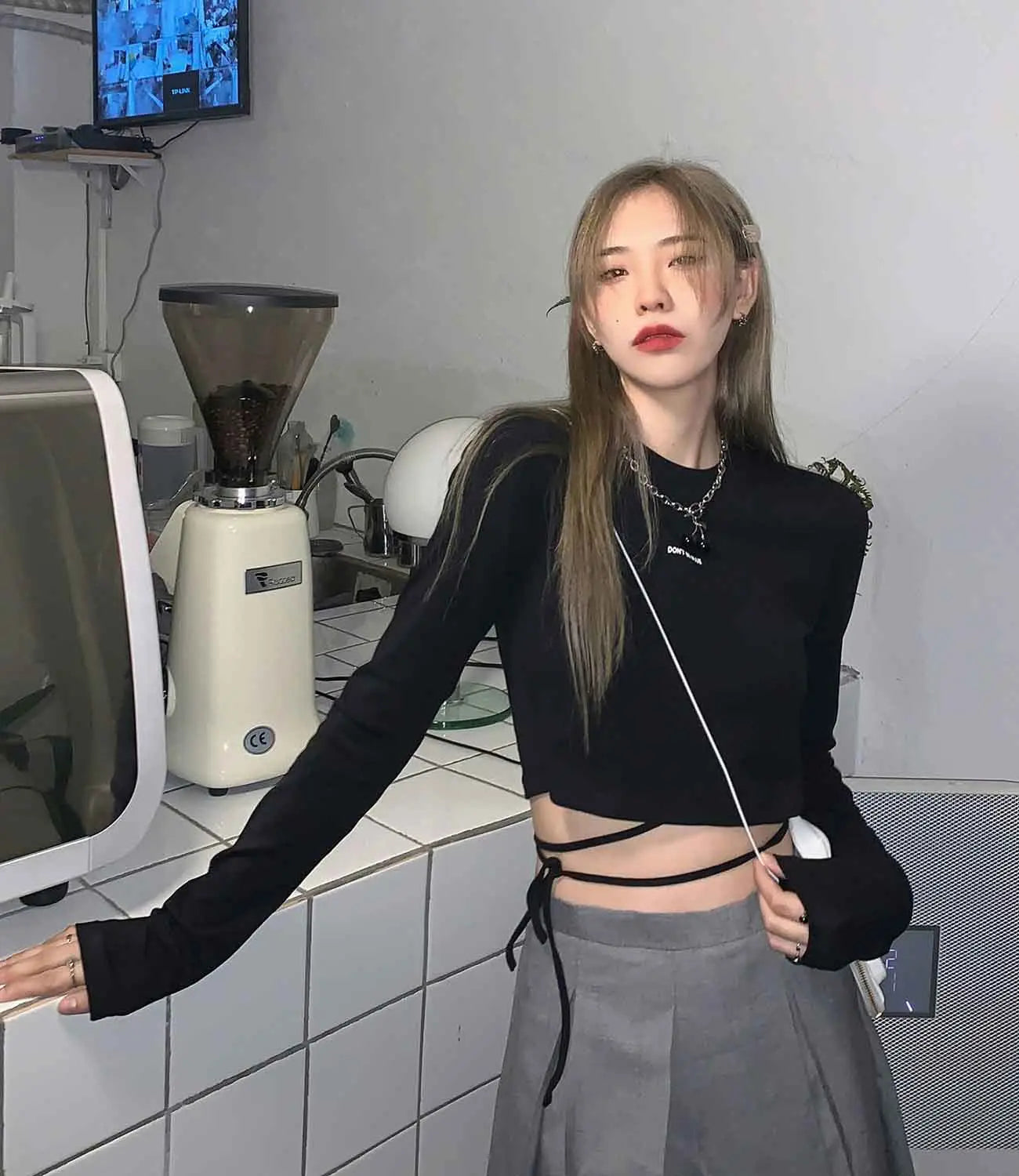Schwarzes Langarm-Crisscross-Crop-Top mit Schnürungen an den Seiten und transparenten Mesh-Ärmeln, für Damen entworfen.