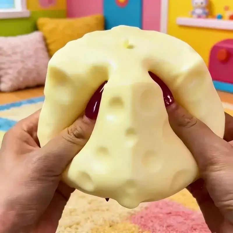 Un juguete antiestrés esponjoso con forma de queso, de color amarillo pálido, con una superficie texturizada y pequeños orificios, diseñado para apretarse.
