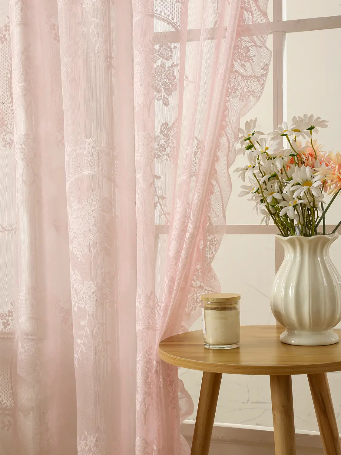 Una cortina semitransparente de encaje rosa delicada, con bordadura floral blanca y detallada e inserciones de encaje, con bolsillo para barra de soporte circular para un arreglo elegante de la ventana.