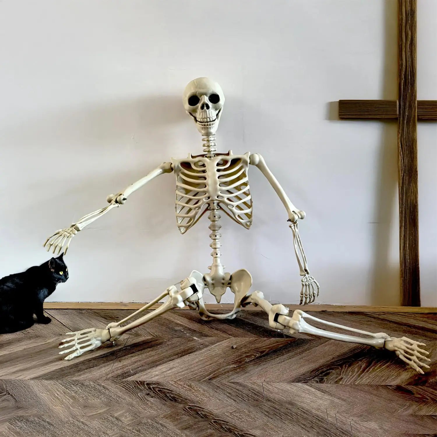una figura modelo de decoración posable de esqueleto de Halloween de plástico color beige, con estructura ósea detallada y extremidades articuladas, sentada en una postura realista para exhibición de casa encantada