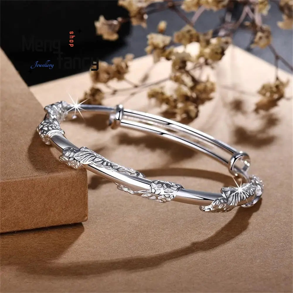Silver bangle bracelet with intricate leaf and floral engravings featuring a sleek adjustable design and adorned with natural jade raw stone for an elegant look.