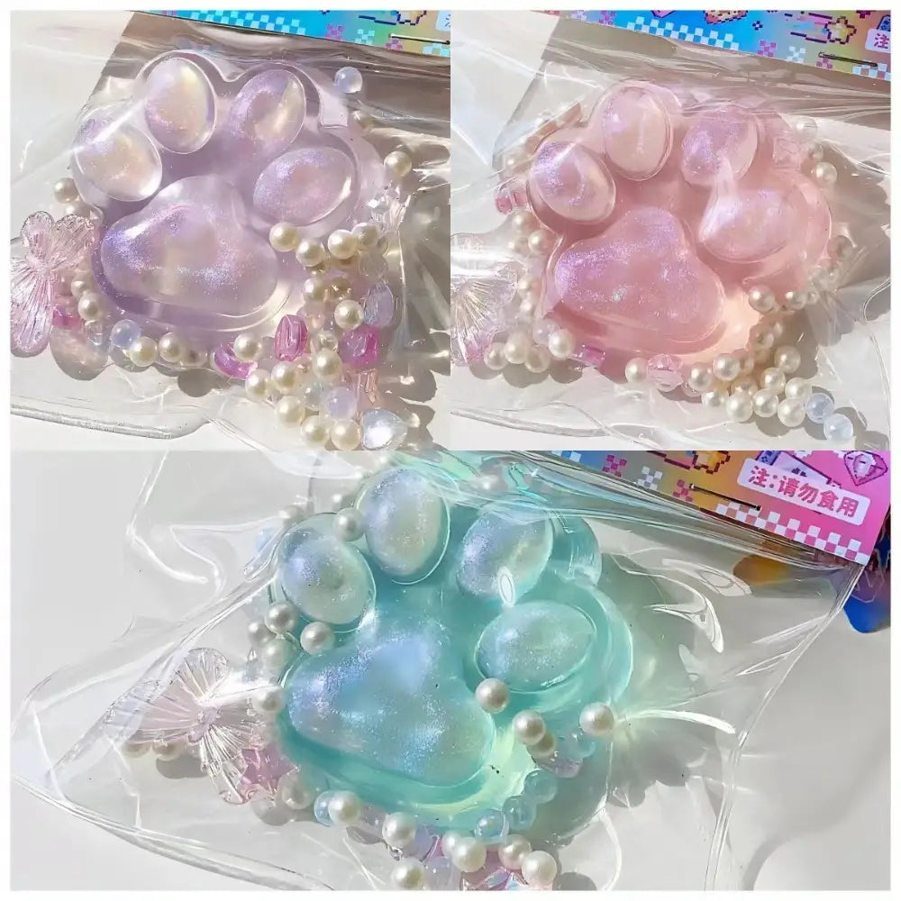 juguete exprimible de resina translúcida con forma de pata de gato de color pastel, adornado con cuentas de aspecto perlado, diseñado para aliviar el estrés de forma gradual y lenta