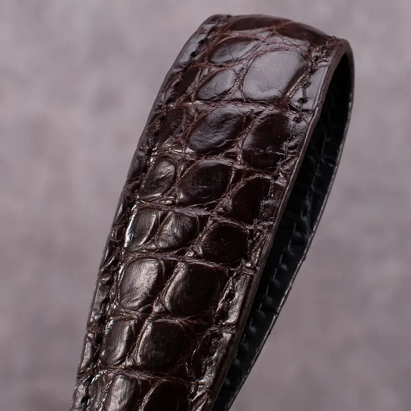 dark brown crocodile leather watch strap with a glossy finish and visible stitching featured alongside the leather tiger head keychain luxury car key ring.