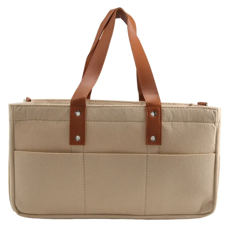 Beige quilted felt baby diaper caddy nursery storage basket with brown leather handles and silver-toned hardware.