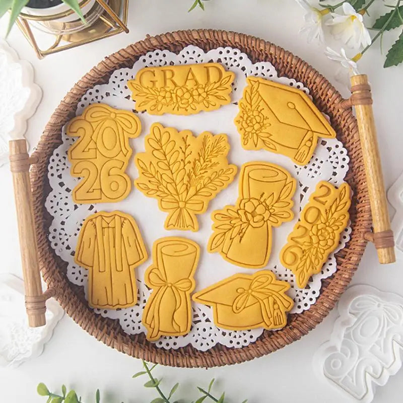 golden 2026 graduation cookie cutter set made of metal arranged on a woven tray for celebratory baking use.