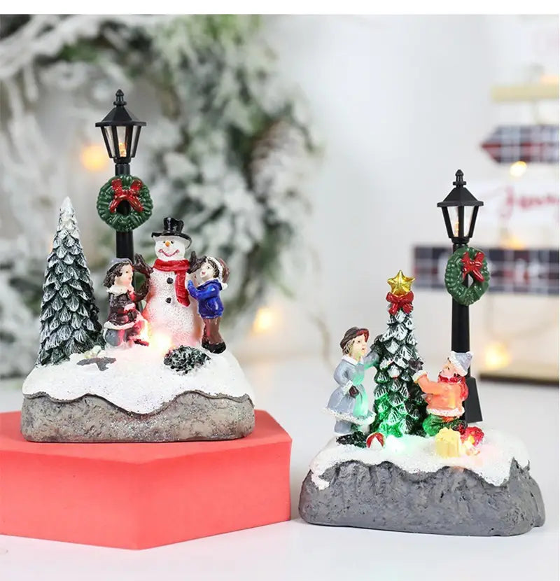 雪の積もった台座上に雪だるまと子どもを配置し、華やかな装飾が施された、クリスマスをテーマにしたミニチュアセットの雪だるまLEDのクリスマスハウスライト用フィギュリンディスプレイ。