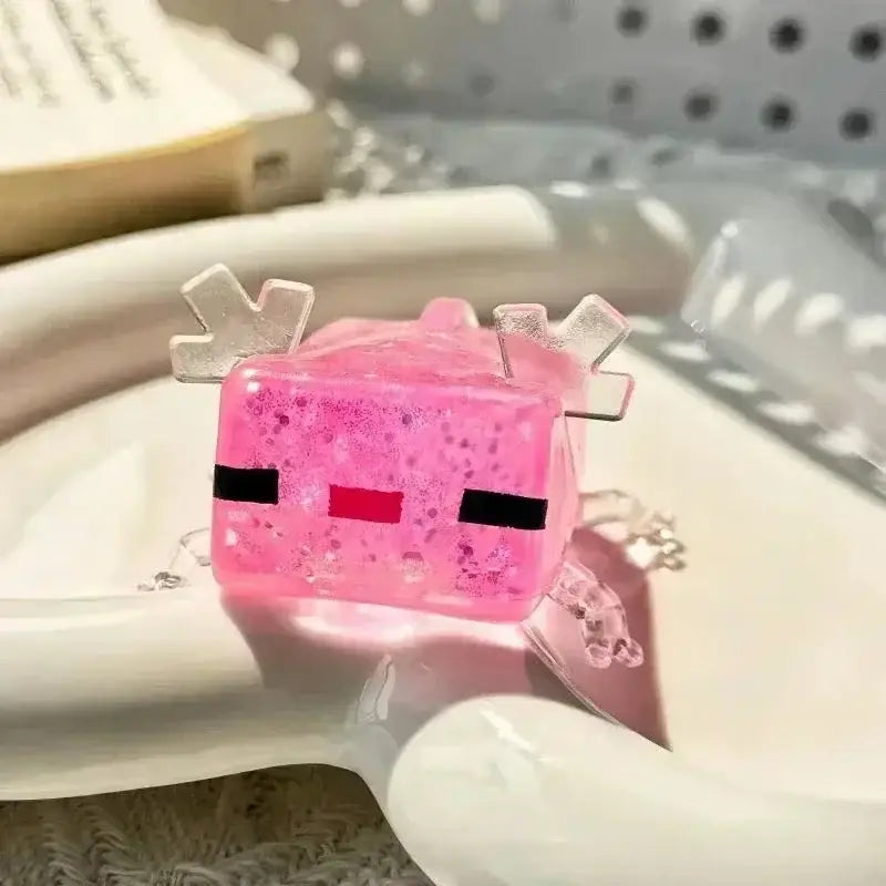 Charmant jouet à mâcher et à malaxer en résine translucide rose, en forme d’axolotl, avec une texture scintillante et de petites appendices en forme de bois de cerf en plastique transparent, utilisé comme jouet à mâcher et à malaxer pour apaiser le stress lié au jouet.