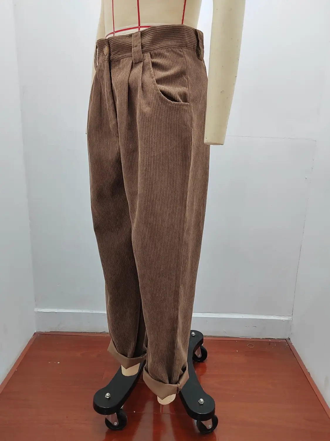 Pantalon en velours côtelé brun taille haute ample avec devant plissé, présenté sur un mannequin.