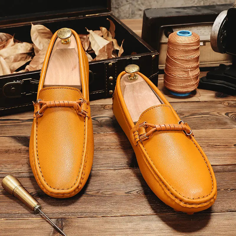 Une paire de chaussures à enfiler habillées en cuir beige pour hommes se portant sans effort avec des chaussures décontractées, présentant des détails de bride tressée et une quincaillerie à tonalité laiton.