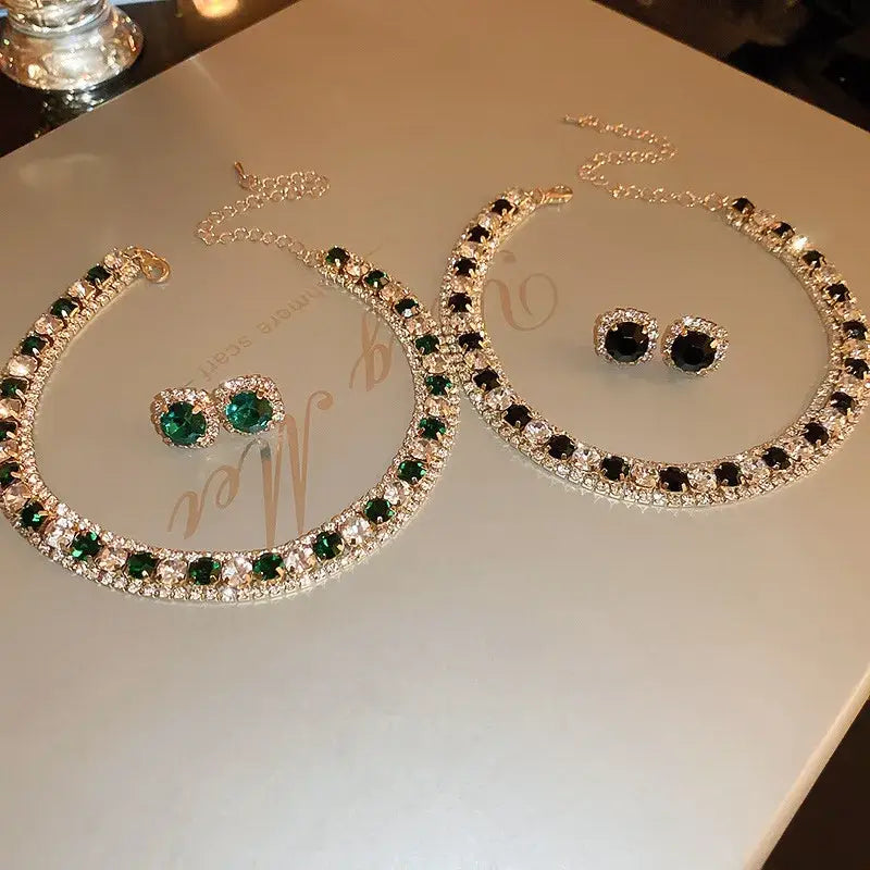 Elegant two-piece crystal necklace and earring set featuring a gold-toned design with alternating emerald green and black rhinestones for pink ab wedding jewelry.