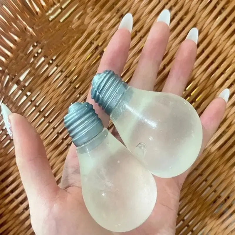 Zwei halbdurchsichtige, frosted Glas-Glühbirnenförmige Sensorik-Fidget-Quetschspielzeuge mit metallisch blauen Schraubsockeln, in der Hand gehalten zur Stresslinderung.