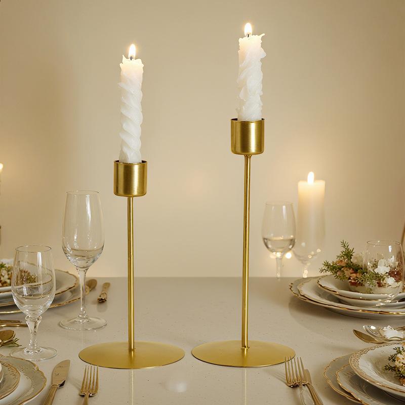 Two elegant gold metal candle holders with white twisted candles designed in European style for home decor.