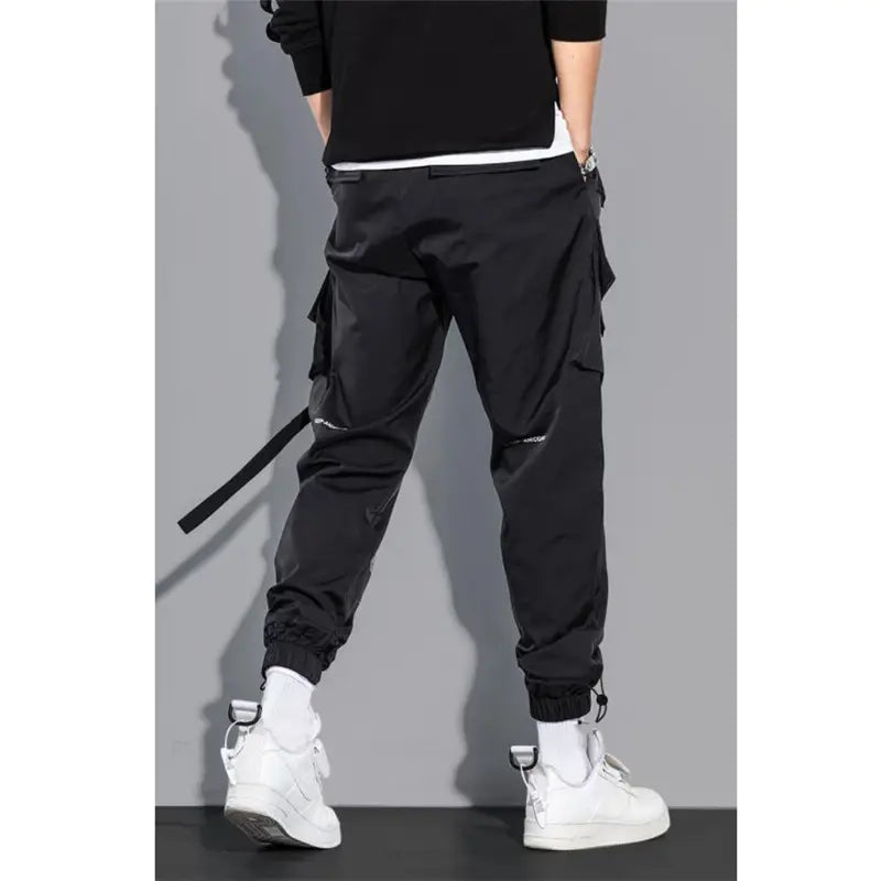 Black mens tactical cargo pants with multiple pockets and a drawstring waistband designed for streetwear use.
