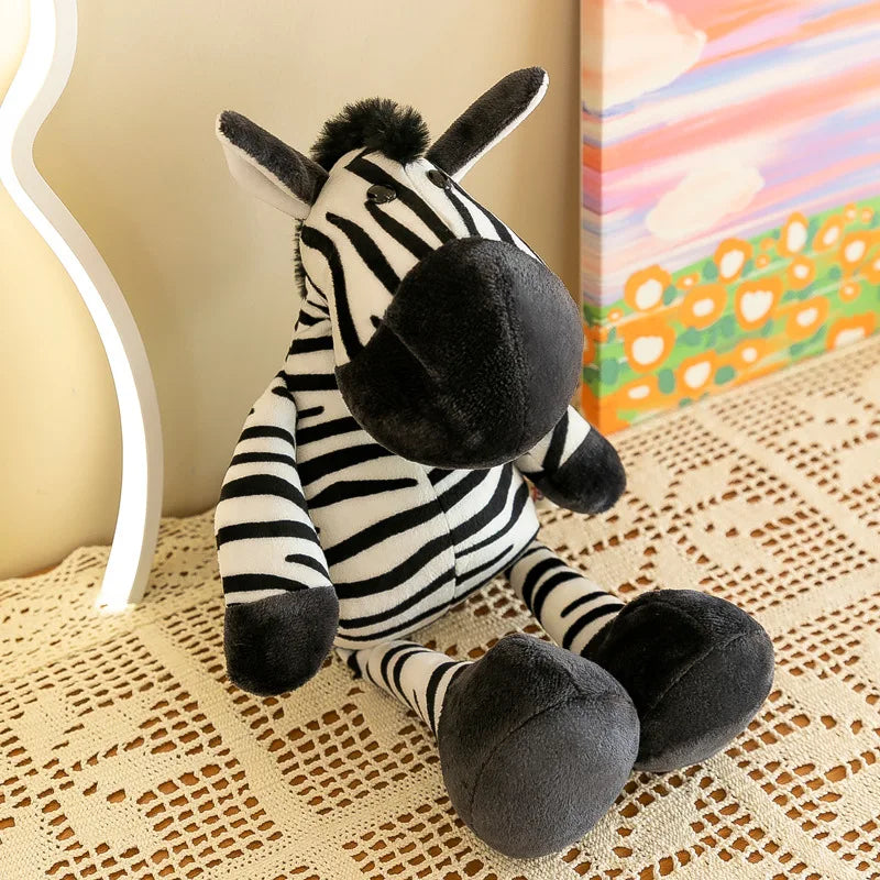 Un peluche de animal de la jungla: una cebra, hecha de una tela suave a franjas negras y blancas, con orejas y nariz de fieltro gris, sentada sobre un mantel de encaje.