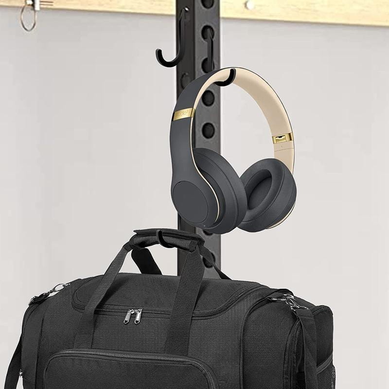 casque audio supra-auriculaire noir et crème, avec finitions dorées, suspendu à un crochet de rangement robuste de rack à squat, conçu comme porte-poids.