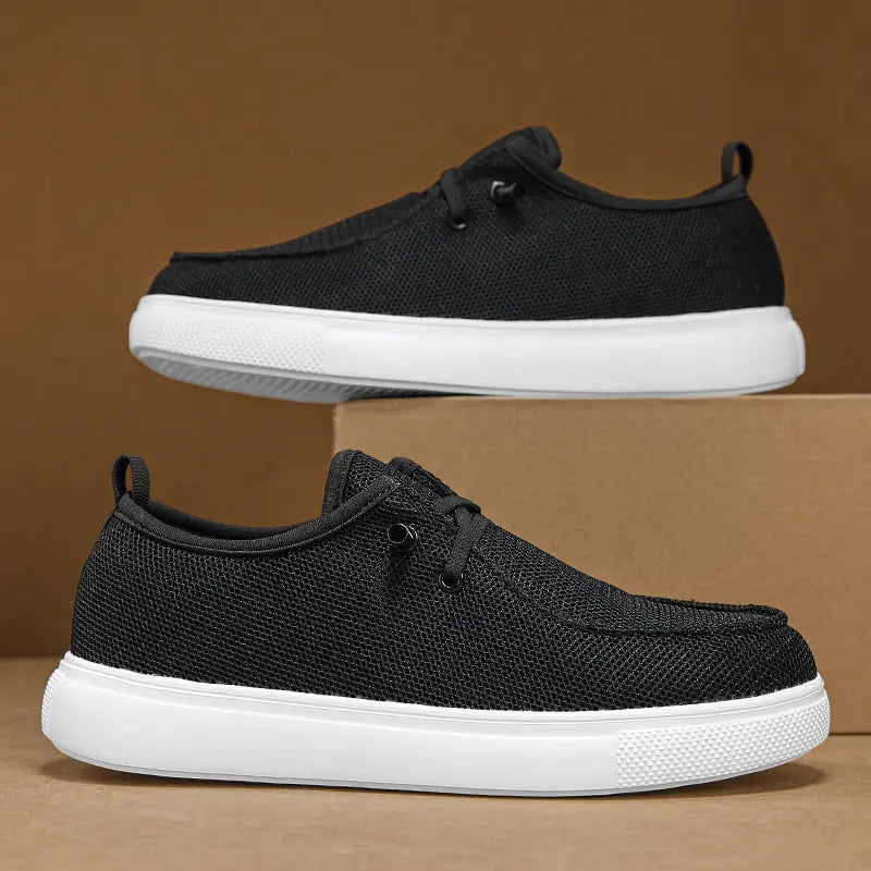 Chaussures de type mocassins décontractées pour hommes en noir, en toile en maille, avec des semelles en caoutchouc blanc et des lacets noirs, pour un port au quotidien.
