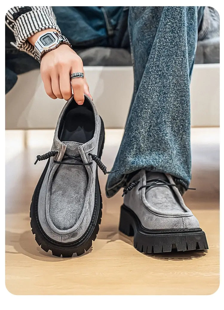Mocassins en suède gris à semelles en caoutchouc noir épaisses et lacets tressés, conçus comme des baskets décontractées à plateforme en suède à semelle épaisse pour hommes.