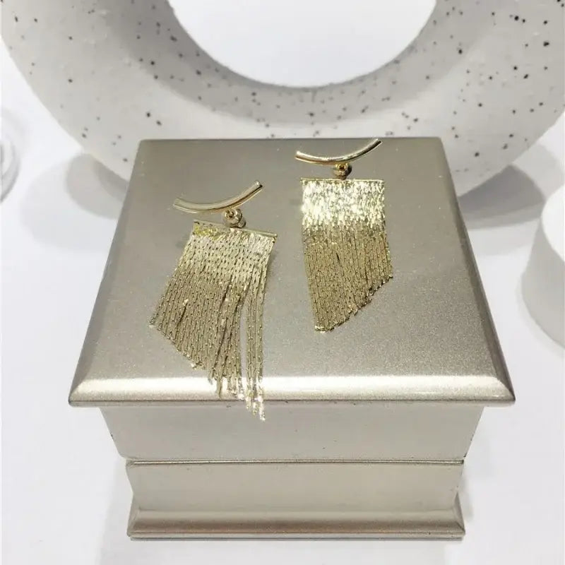 Boucles d’oreilles déclaration à frange en or, avec une frange dorée texturée et un crochet supérieur incurvé.