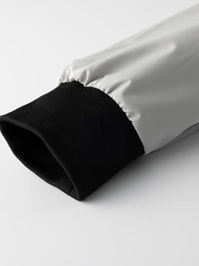 the sleeve cuff of a white and black windbreaker waterproof hiking jacket for men features a smooth satin-like outer fabric with a ribbed knit inner lining suitable for autumn hiking.