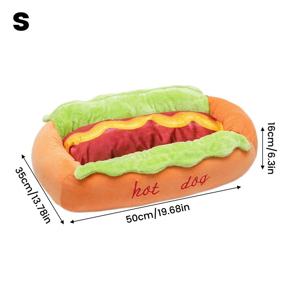 orange plush hot dog-shaped pet bed with green lettuce and yellow mustard details featuring hot dog embroidered in red script designed as a comfortable resting place for cats and dogs.