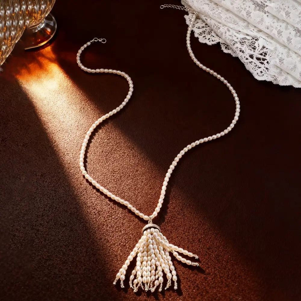 Collier-ras-de-cou à pendentif pompon de perles, longue chaîne de pull-over, avec une chaînette fine et délicate, agrémentée de rangées retombantes de perles blanches luisantes.