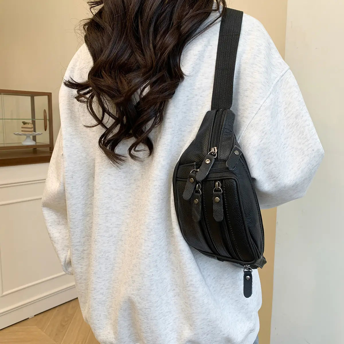 Schwarze Gürteltasche aus echtem Leder mit mehreren Reißverschlüssen und einer strukturierten Oberfläche, entworfen als stilvolle Crossbody-Bauchtasche.