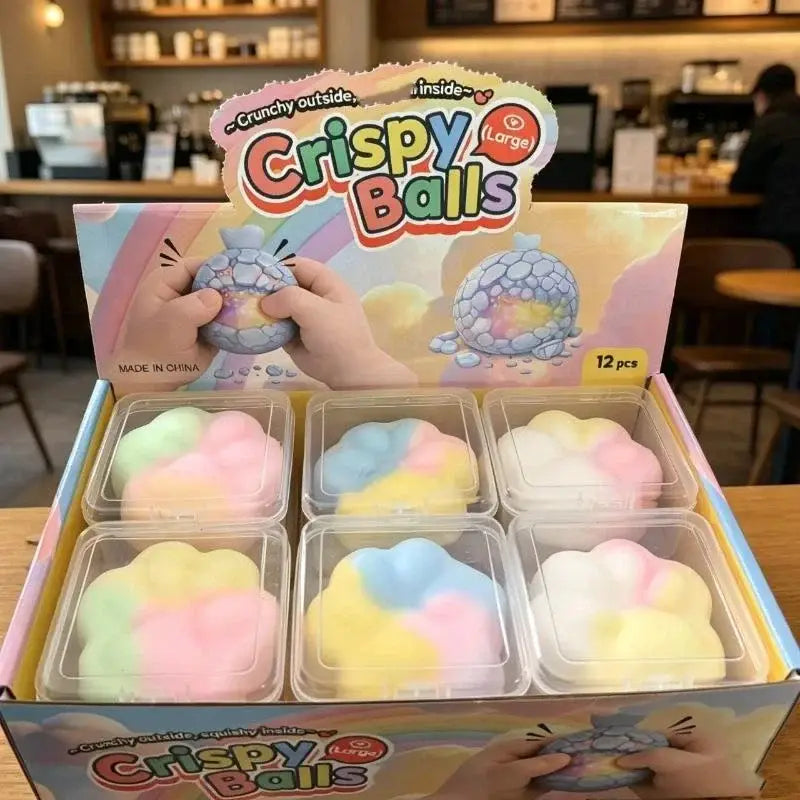 jouet antistress d’aspect pastel, petites balles souples à presser, fabriquées en plastique sans BPA, avec une enveloppe extérieure croquante et un intérieur doux, conditionné dans des boîtes transparentes à l’intérieur d’un présentoir en carton coloré.