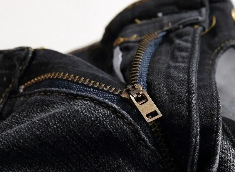 Jeans de moto pour hommes, coupe slim délavée, en denim foncé, présentant une fermeture éclair de couleur laiton, des surpiqûres visibles et une texture du tissu.