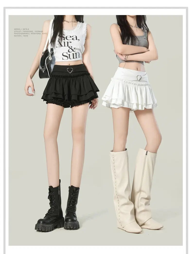 Black ruffled high waist mini skirt featuring a heart-shaped metal accent at the waistband in a Y2k style.