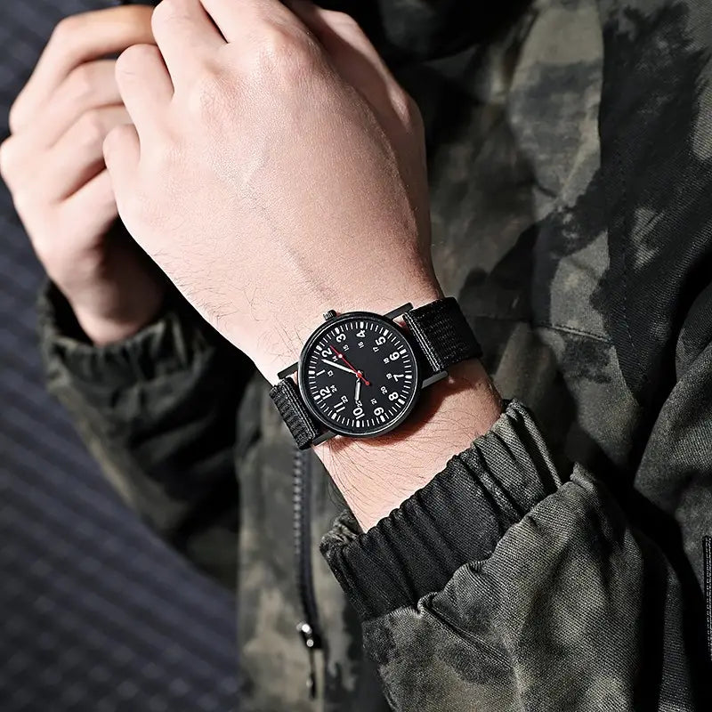 Militärisches Quarzarmbanduhr mit schwarzem NATO-Armband, matt schwarzem Zifferblatt, weißen arabischen Ziffern und rotem Sekundenzeiger.