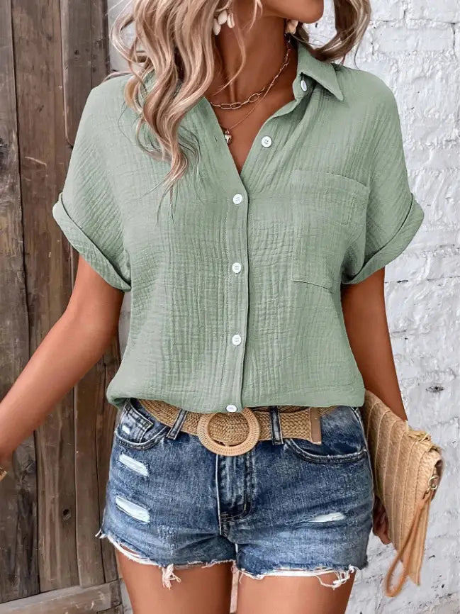 A light green women cotton short sleeve button up shirt with subtle textured fabric and rolled cuffs.