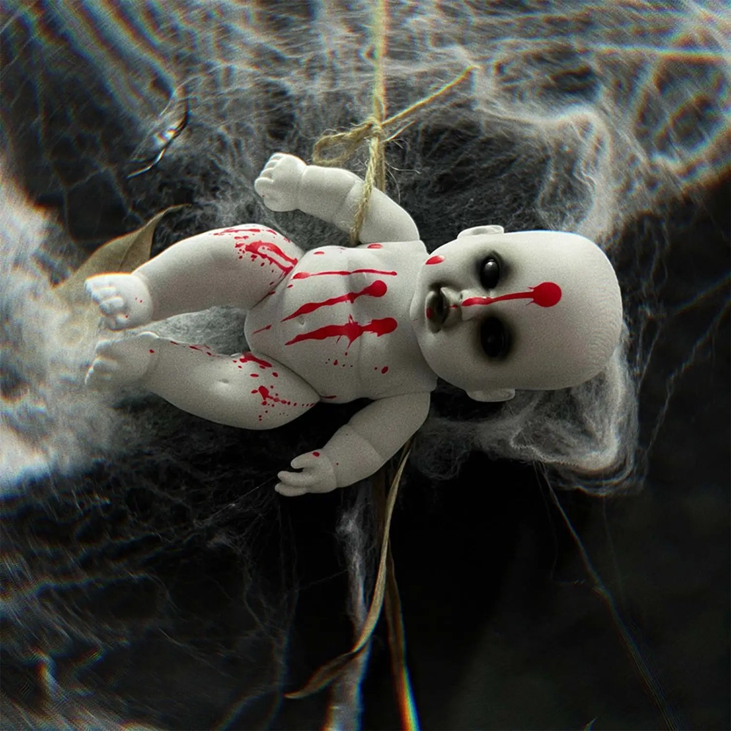 halloween hanging ghost doll spooky prop featuring a white porcelain baby doll with black eyes and red paint splatters suspended by a string in a webbed setting.