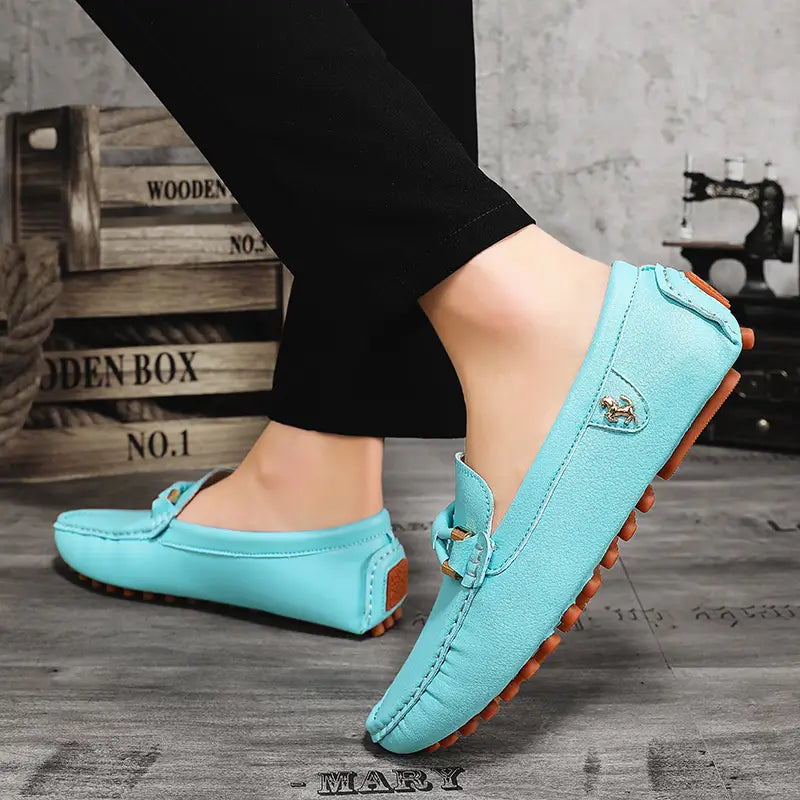 Chaussures à enfiler habillées en cuir suédé bleu clair pour hommes, avec des semelles en caoutchouc marron et un petit emblème équestre métallique pour un port décontracté sans effort.