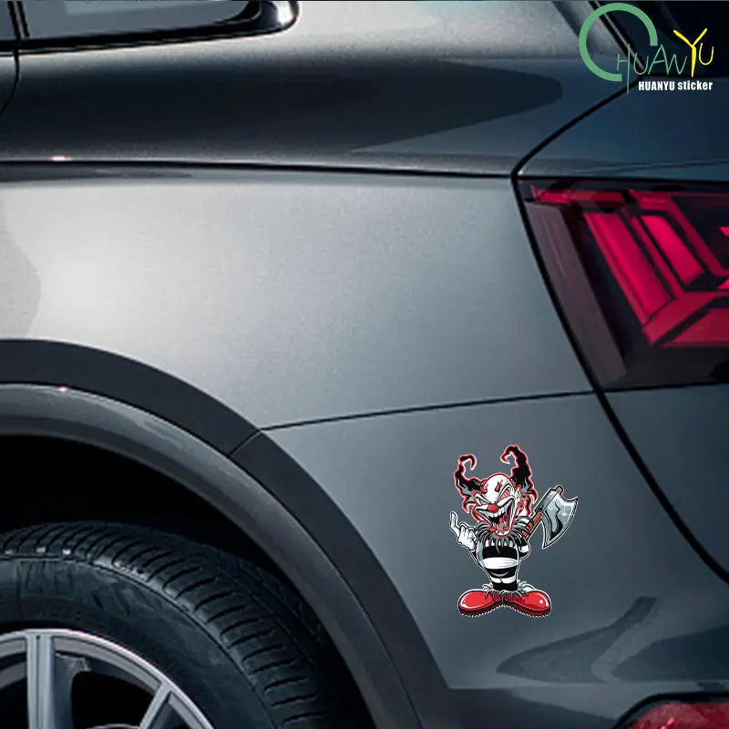 Autocollant de voiture de clown maléfique de dessin animé rouge et noir vibrant avec une grimace menaçante tenant une hache, en autocollant imperméable.