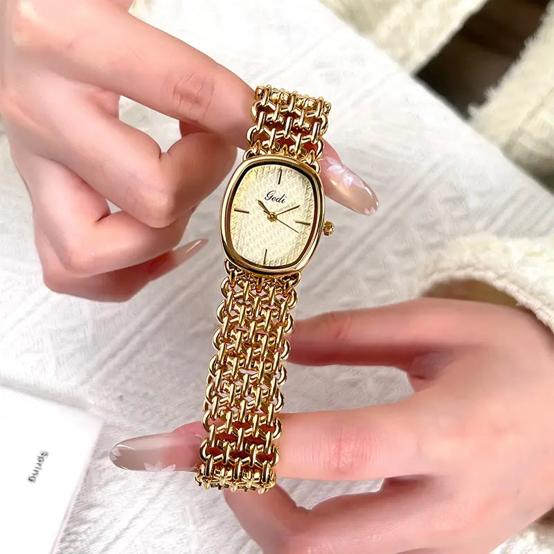Gold-toned chain-link bracelet watch with an oval face and subtle textured dial featuring the brand name gedi at its center.