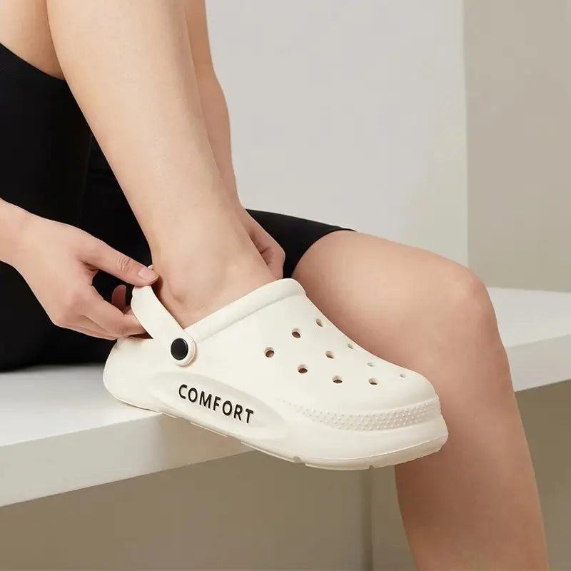 Weiße Eva Slip-on Cushion Clog-Sandale mit perforiertem Obermaterial und schwarzer Komfort-Schriftzug-Aufschrift auf dem weißen Gummimaterial.
