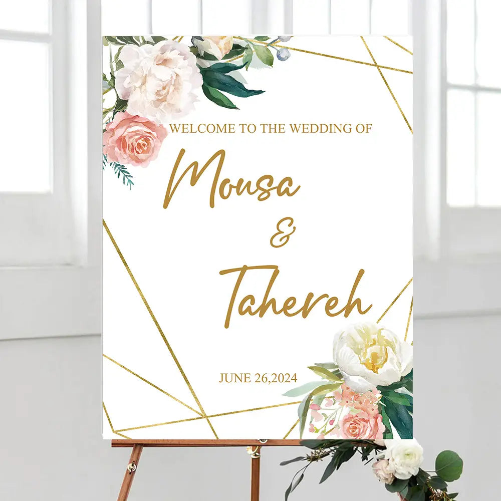 Un panneau d’accueil de mariage blanc sur mesure en mousse, avec des lignes géométriques dorées et des accents floraux à l’aquarelle, présentant les noms Mousa et Tahereh dans une élégante écriture dorée en script.