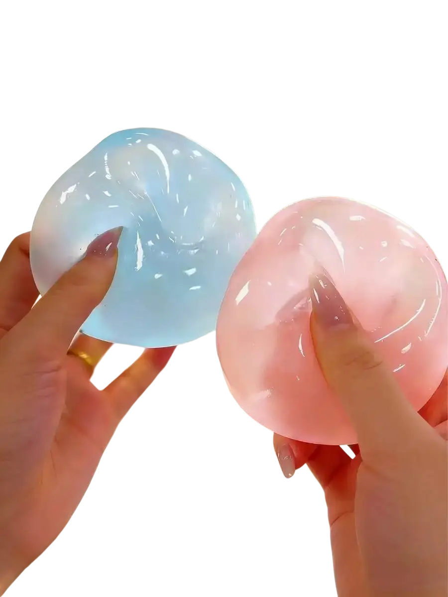 Two translucent moldable slow rebound stress balls in light blue and pink held in hands with manicured nails front view