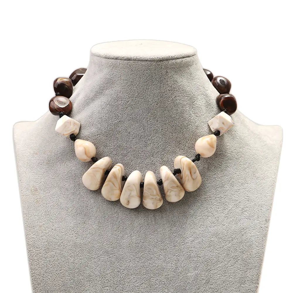 Collier ras du cou en résine à motif géométrique, fait de perles marbrées, présentant une disposition audacieuse de perles en forme de goutte marbrée couleur crème et de perles rondes brillantes brun foncé, enfilées sur un cordon noir.