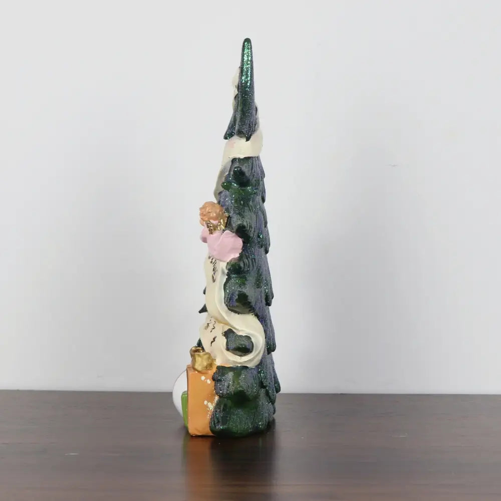 Eine glänzende, dunkelgrüne Harz-Glitzer-Engel-Weihnachtsbaum-Figurine, geschmückt mit einer weißen Schleife, einer rosafarbenen Blume und miniaturgroßen Geschenkboxen.