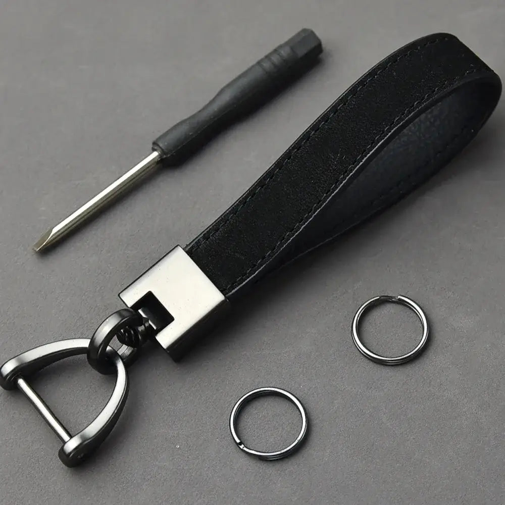 Schwarzer Lederschlüsselanhänger aus echtem Leder mit einem D-Ring aus silberfarben wirkendem Metall und rechteckigem Verbindungsstück; minimalistischem Schlüsselring.