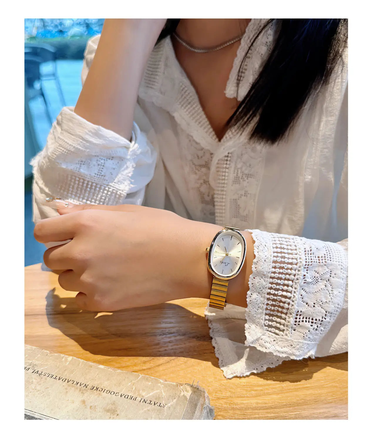 女性向けのゴールドミニマリスト楕円形クォーツウォッチ。ゴールドトーンの長方形ケース、ホワイトダイヤル、手首に着用する細身のメタリックブレスレットを特徴とします。